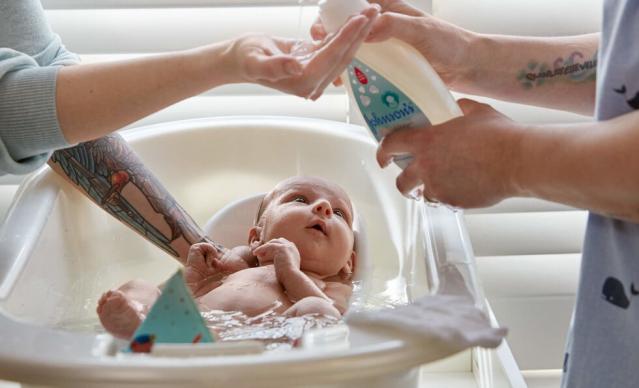 Bathing newborn with Johnson'sÂ® CottonTouchâ„¢ newborn wash & shampoo